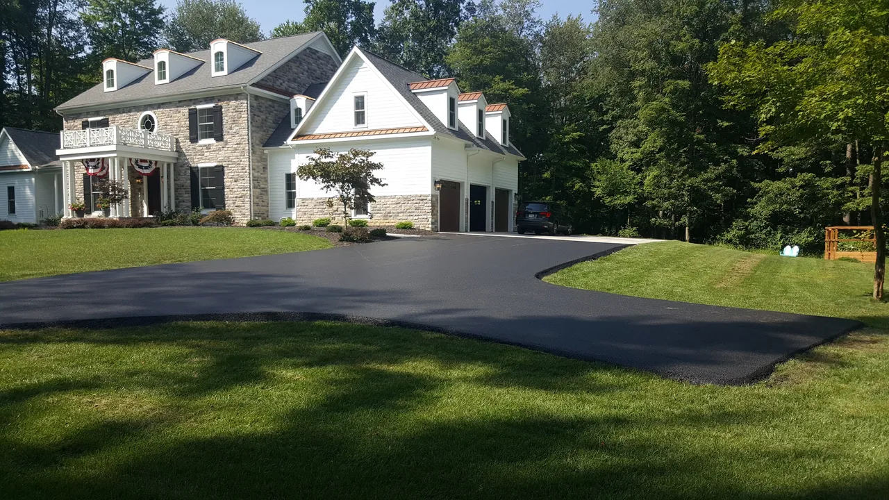 Custom asphalt driveway at a stone and white home